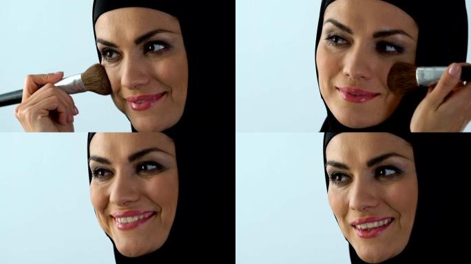 30多岁的微笑的穆斯林妇女涂腮红，抗衰老化妆品，化妆