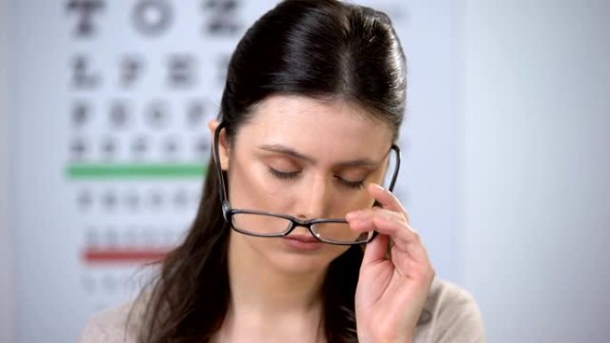 不快乐的女人摘下眼镜，承受高压，有失明的危险