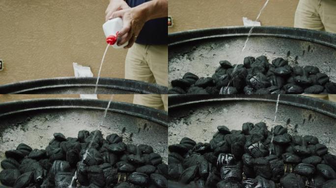 一名五十多岁的白人男子将液体打火机液体(引火器)从塑料瓶里喷到户外烧烤架上的煤块上，准备烧烤