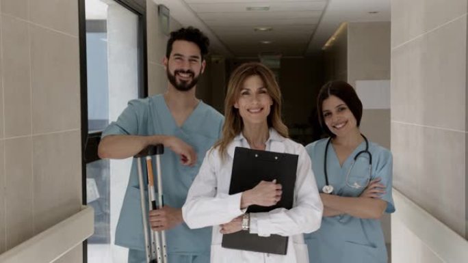 医院医生，女和男护士的开朗团队面对镜头微笑，双臂交叉