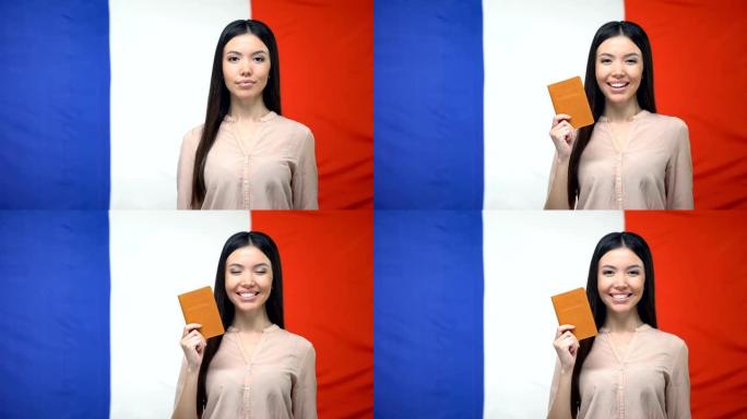 微笑的女人拿着护照，以法国国旗为背景，出国旅行