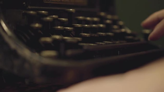 女性双手在旧打字机上用字母特写慢慢打字。