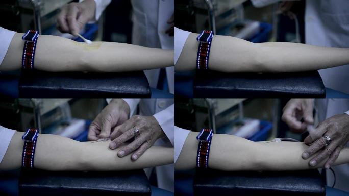 技术员将针头插入献血者的手臂，在医院的血库实验室进行血液检查