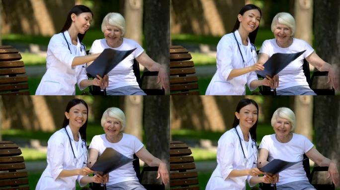 微笑的女医生给坐在轮椅上的快乐老妇看脊柱x光
