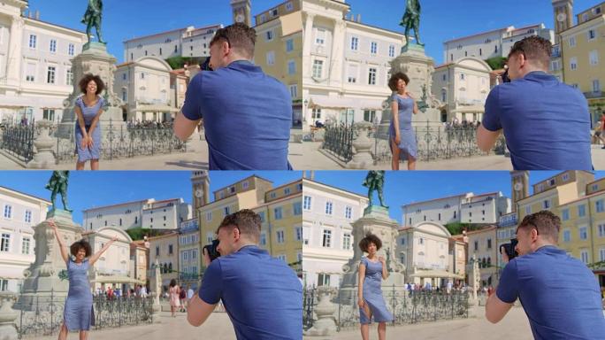 年轻的白人男子在阳光明媚的日子在城镇广场的雕像前为女友拍照
