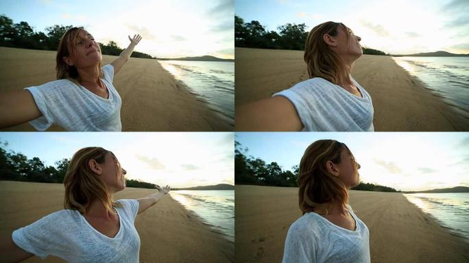 年轻女子的手臂在日出时在海滩上伸出