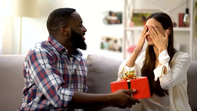 黑人男性向惊讶的女友赠送礼品盒，庆祝生日