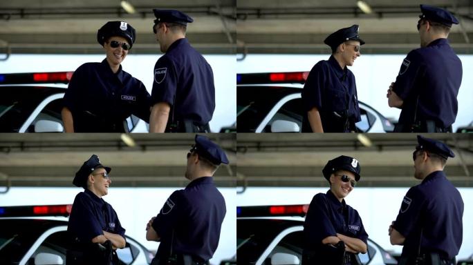 女警和她的伴侣聊天，笑着站在巡逻车附近，休息