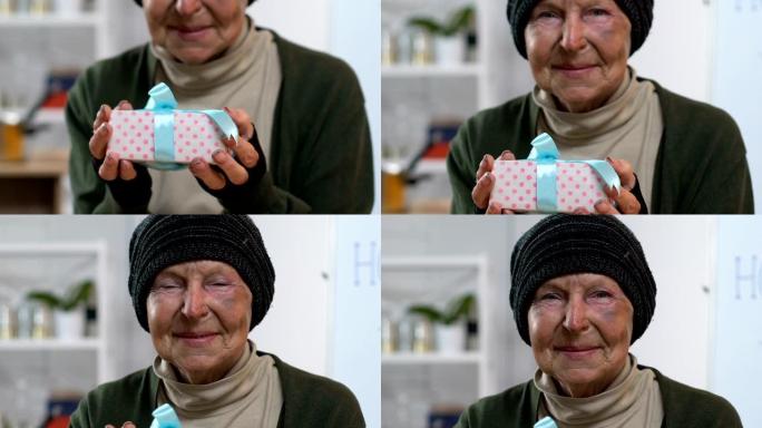 微笑的无家可归的女人拿着礼品盒，看着镜头，惊喜