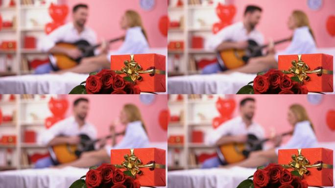 红色礼品盒和一束玫瑰特写，男性弹吉他浪漫旋律