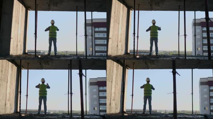 日落时建筑物屋顶上的工程师建设者站在VR眼镜中，并使用未来的界面移动双手。未来的未来工程师。从后面看