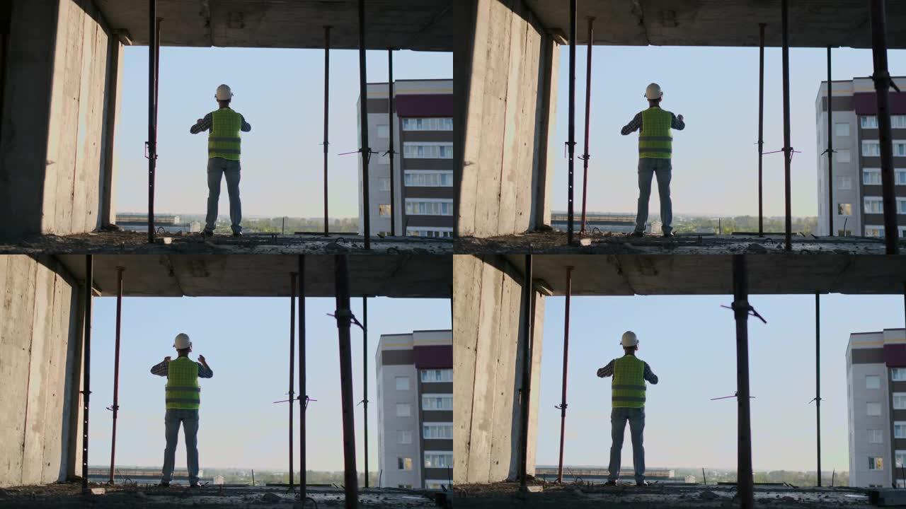 日落时建筑物屋顶上的工程师建设者站在VR眼镜中，并使用未来的界面移动双手。未来的未来工程师。从后面看