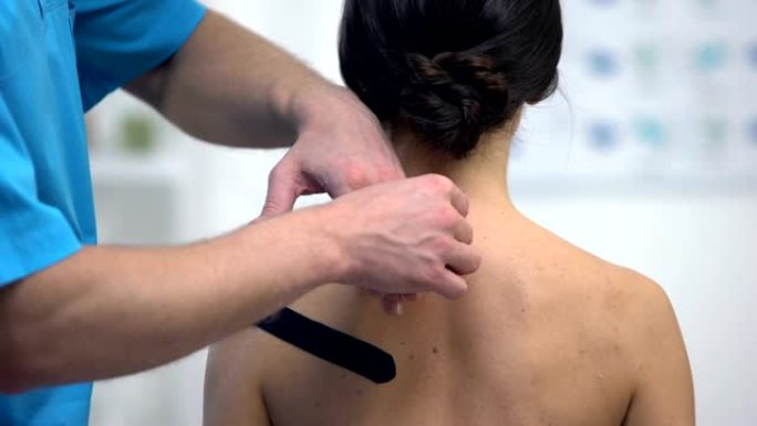 理疗师在女性患者肩部肌肉劳损上使用y型胶带