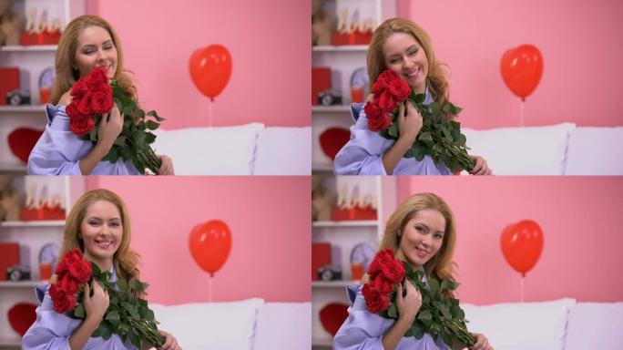 幸福美丽的女人捧着一束红玫瑰对着镜头微笑，浪漫