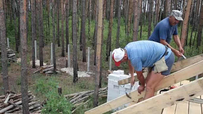 屋顶工在屋顶上工作。建筑商用锤子锤钉子。