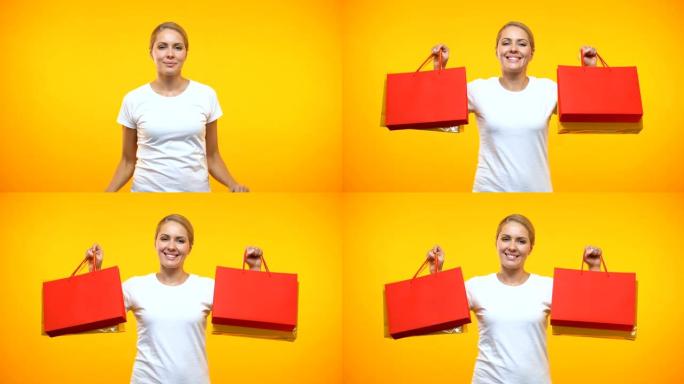 微笑的漂亮女士在橙色背景上展示购物袋，假日大甩卖