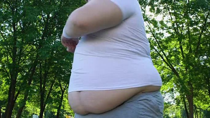 大肚子的胖乎乎的男人在城市公园做早操，每天锻炼