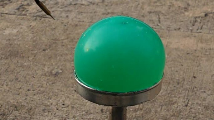 飞镖刺穿绿色水气球的慢动作