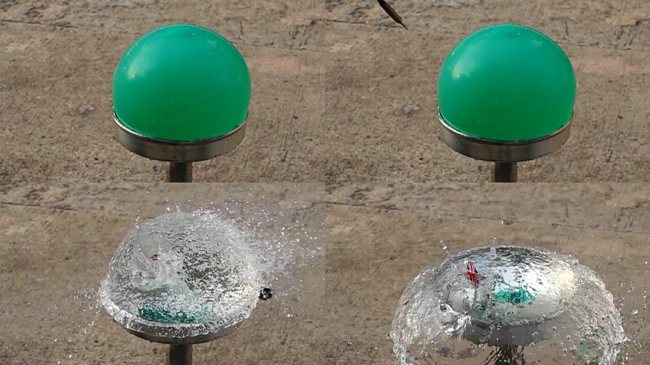 飞镖刺穿绿色水气球的慢动作