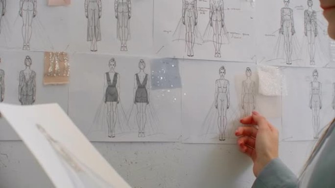 女时装设计师正在为她的最新系列选择并悬挂服装素描。轻质织物。女时装设计师正在选择