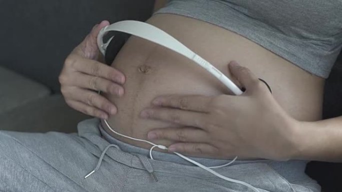 孕妇通过耳机为未出生的婴儿播放音乐
