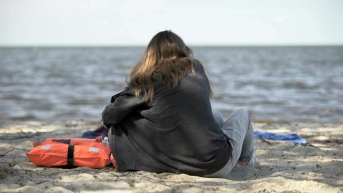 母女俩坐在海边的救生衣旁，幸免于难