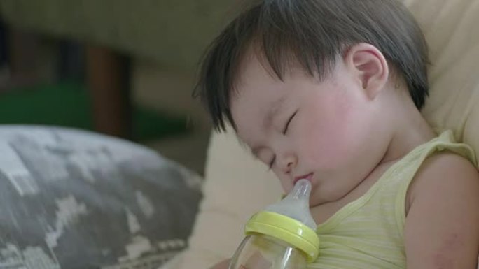 日本婴儿一边喝牛奶一边睡觉。侧视图。