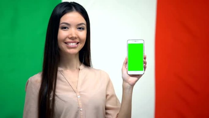 女孩显示绿屏手机，背景上有意大利国旗，翻译