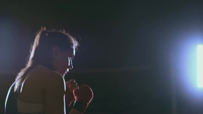 在黑暗的房间里训练一个漂亮的女拳击手。斯蒂安卡姆开枪。备战自卫战环