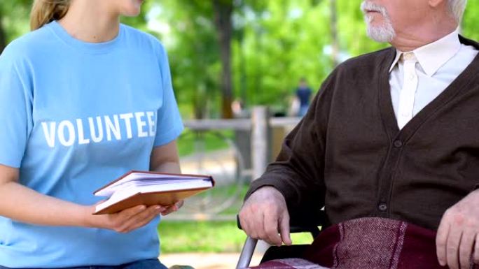 真诚的社会工作者为公园的残疾养老金领取者阅读书籍，志愿服务