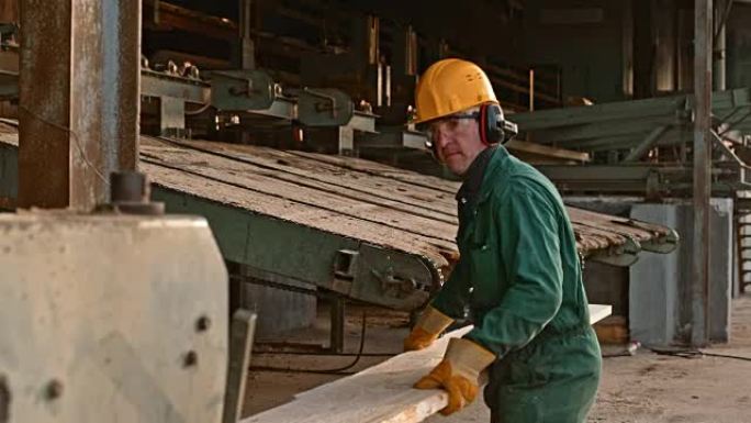 使用木材磨边机的男性锯木厂工人