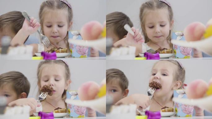 可爱的高加索女孩享受美味蛋糕的特写肖像。深灰色眼睛的孩子坐在桌子旁吃饭。幸福、休闲、生活方式。