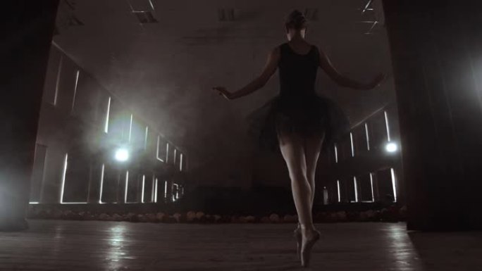 慢动作: 穿着黑色连衣裙的芭蕾舞女演员表演旋转和优美的舞蹈动作。摄像机在万向节上移动。