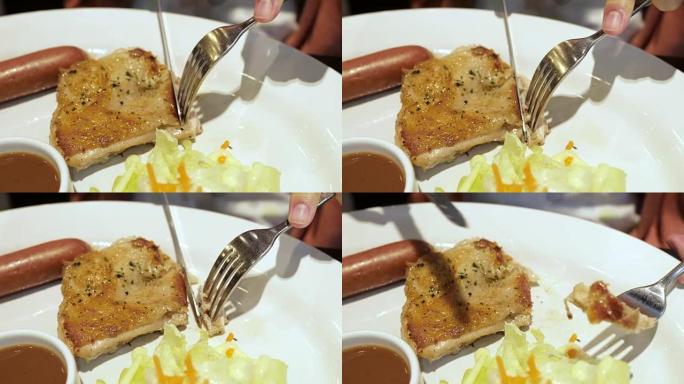 关闭一个男性的手切和吃美味的沙拉与刀和叉子鸡排。