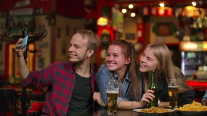 一群朋友男人和两个女孩在酒吧里笑着拍照。在酒吧和傻子在一起。