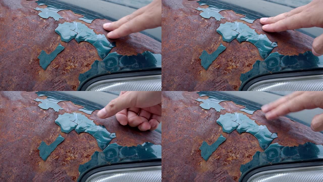 4k修理工用手触摸生锈的旧车，油漆脱落。处于淡色状态的旧绿色汽车