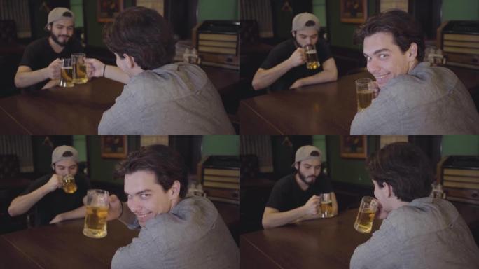 两个家伙坐在酒吧的桌子旁喝啤酒碰杯。