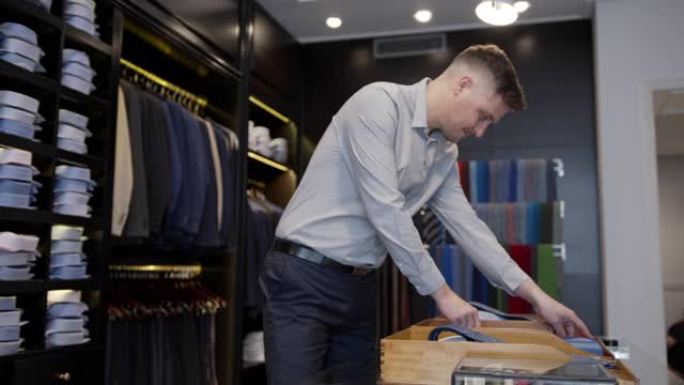 英俊的推销员在男装店组织领带展示