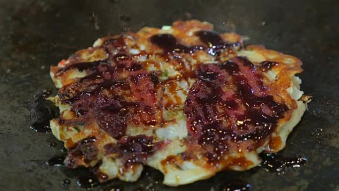 在铁板烧锅上制作okonomiyaki。前视图。