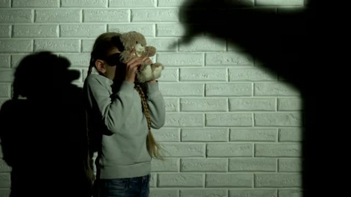 害怕的女孩用泰迪熊遮住眼睛，墙上的鬼影，噩梦