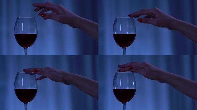 修过完美指甲的女人的手用红酒诱惑地触碰酒杯