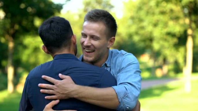 两个男性朋友突然在户外相聚拥抱，愉悦情绪