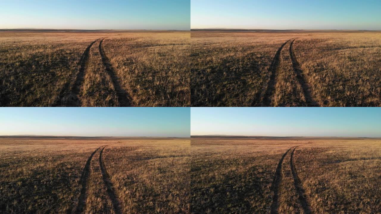 在日落/日出时，在晴朗的蓝天下，在犹他州的沙漠平原上，一对轮胎痕迹的上升空中无人机拍摄