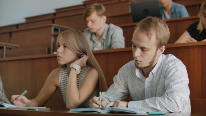 学生在其中听老师讲课并在笔记本上写短片报告的学院当前观众。传授知识，教育学生