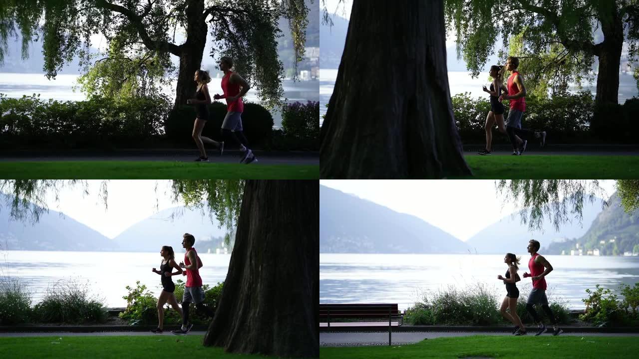 年轻夫妇在山下日出时沿着湖边小路慢跑