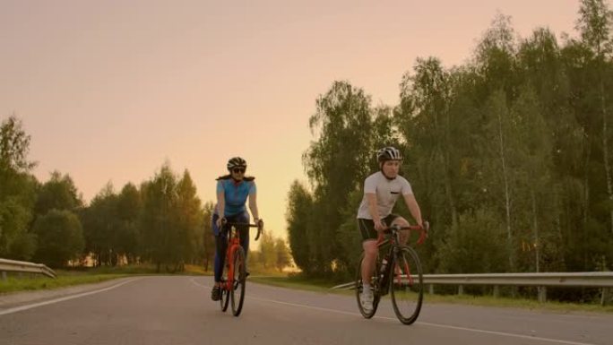 空的空间。日落时骑自行车的运动朋友。几个骑自行车的人沿着海岸去。自然背景下的运动。一群人在日落时骑自