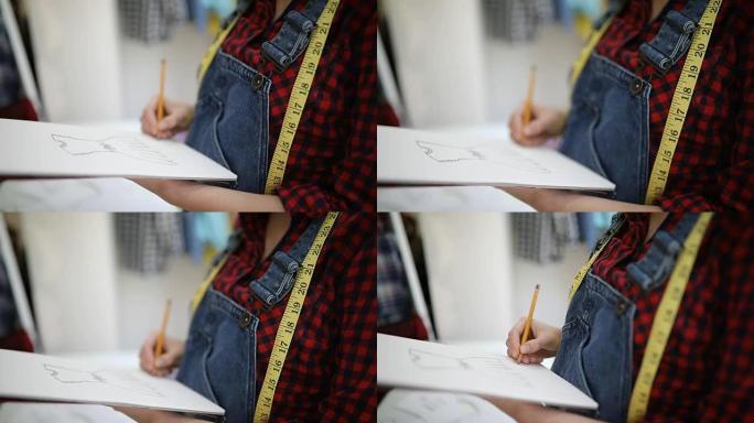 女性时装设计师双手握着画板和钢笔制作新衣服的草图。
