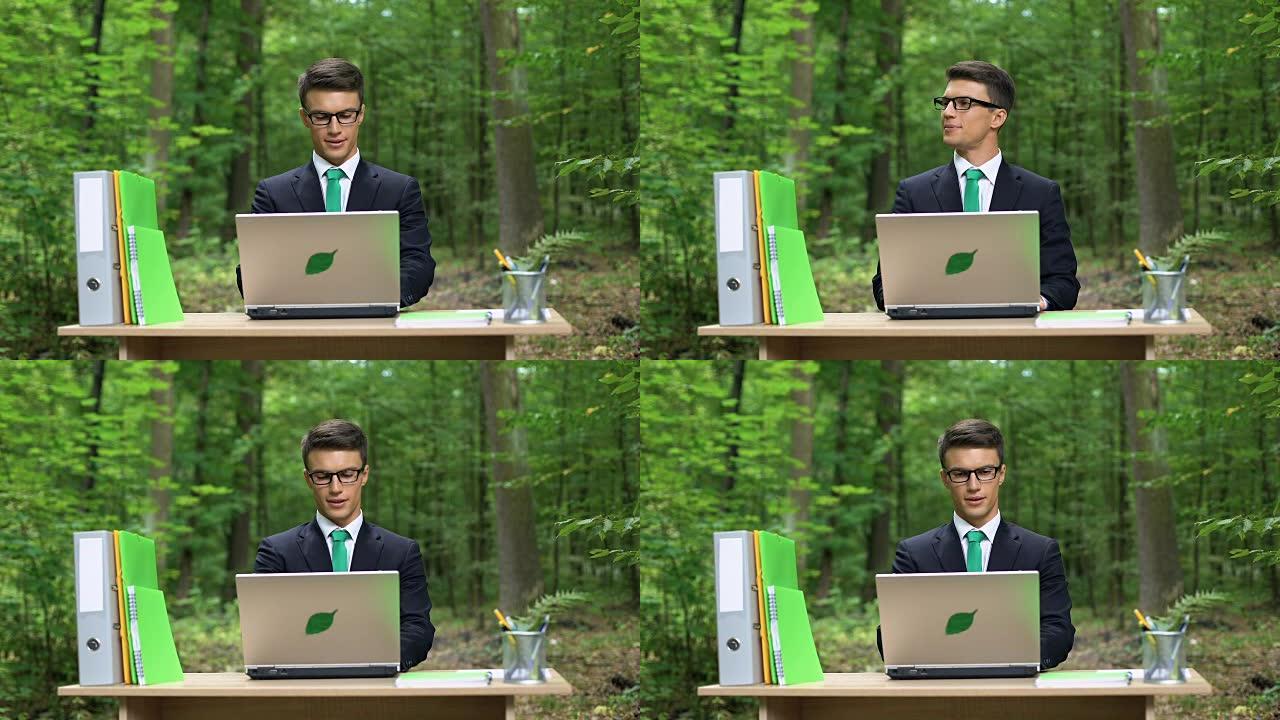 忙碌的人坐在办公桌前，在绿色公园工作节能笔记本电脑