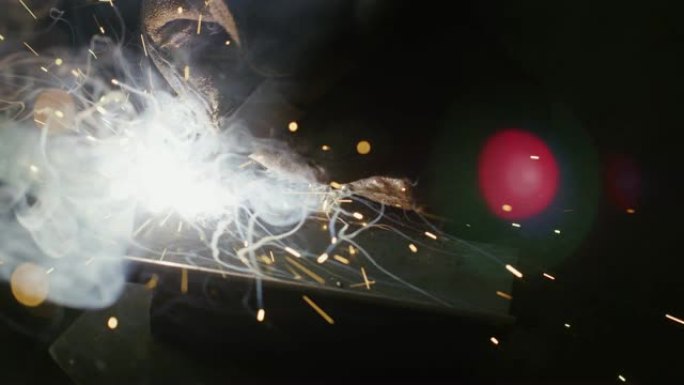 火花飞舞时，一个人在车间的金属焊接台上焊接MIG