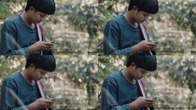 年轻的亚洲农民在智能手机上发短信